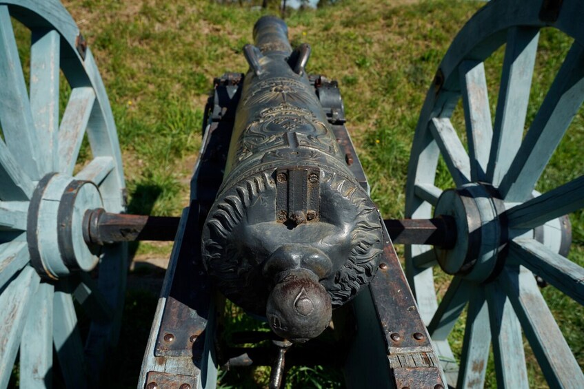Eine Kanone mit einem Löwenkopf, montiert auf einem Wagen mit blauen Rädern. 5