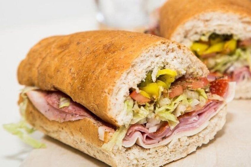 Un sándwich con ingredientes visibles como lechuga, tomate y jamón. 3
