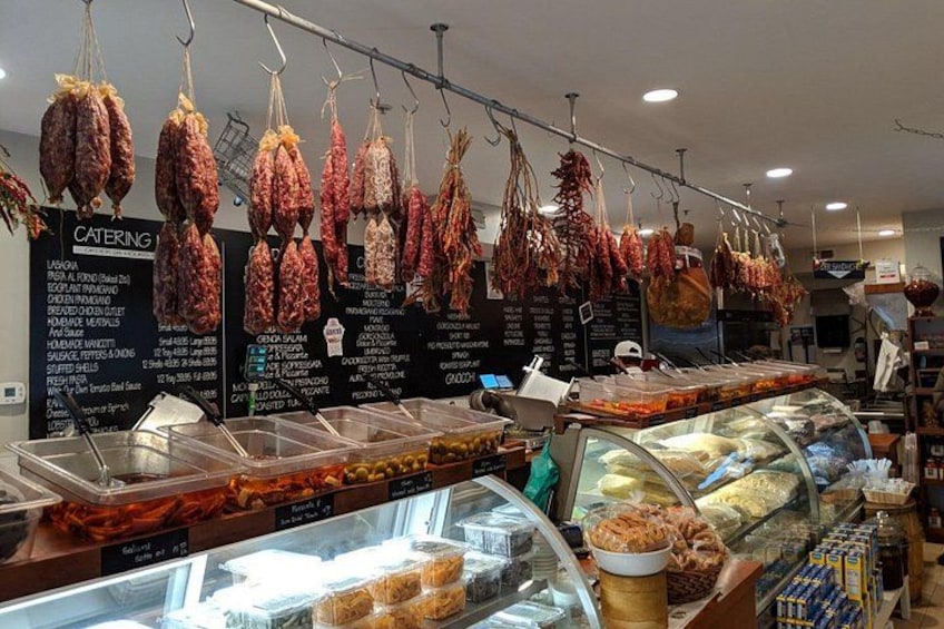 A deli with various meats hanging and displayed in glass cases. 5