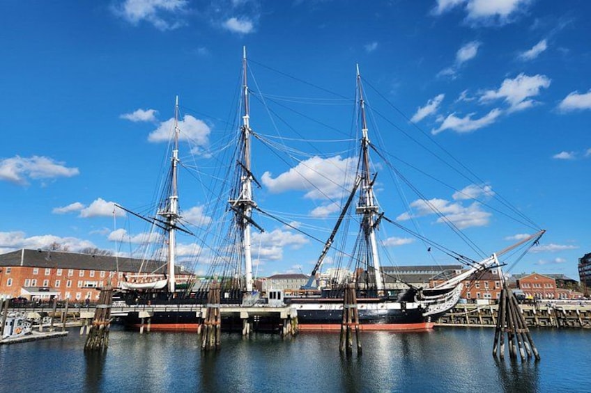 A large sailing ship docked at a harbor with buildings in the background. 4