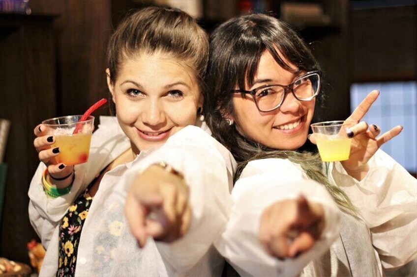 Two people holding drinks and pointing at the camera. 5