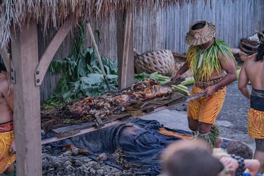 Une scène de cuisine traditionnelle mettant en scène un gros poisson sur une plateforme en bois, entouré de personnes. 3