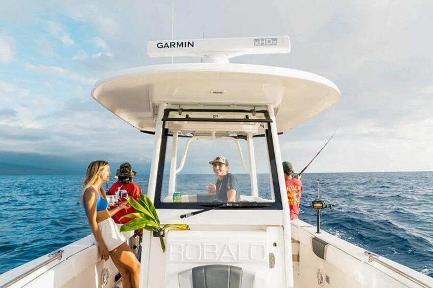 A boat with a Garmin navigation system, a person steering, and another person fishing. 2