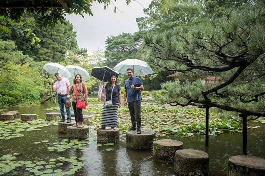 People standing on stone platforms over water with lily pads, surrounded by trees and greenery. 4