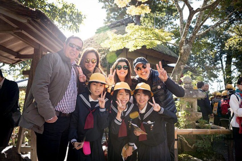 A group of people posing for a photo in a park with trees and a wooden structure in the background. 5