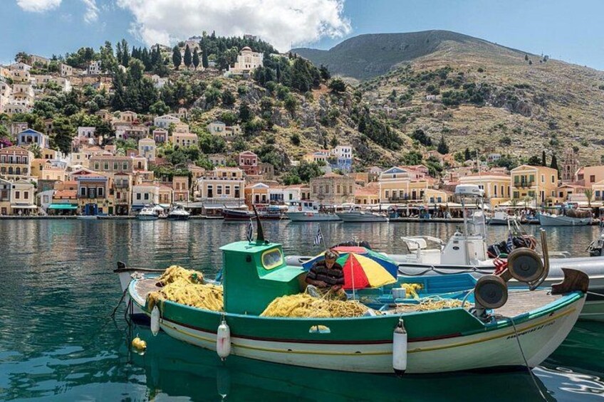Un pueblo costero con edificios coloridos, un puerto con barcos y una colina al fondo. 4