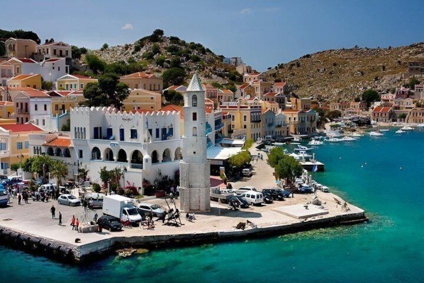 A coastal town with a prominent white tower, colorful buildings, and a marina. 3