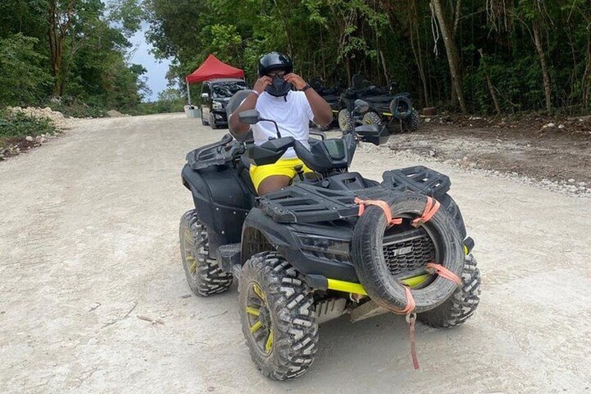 A person on a quad bike with yellow accents, a red tent, and trees in the background. 2