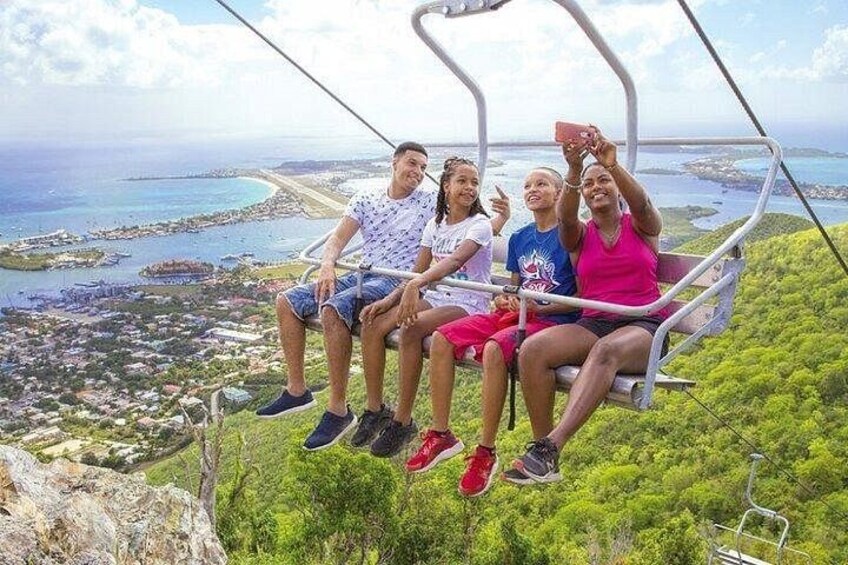 A group of people on a cable car with a coastal landscape in the background. 1
