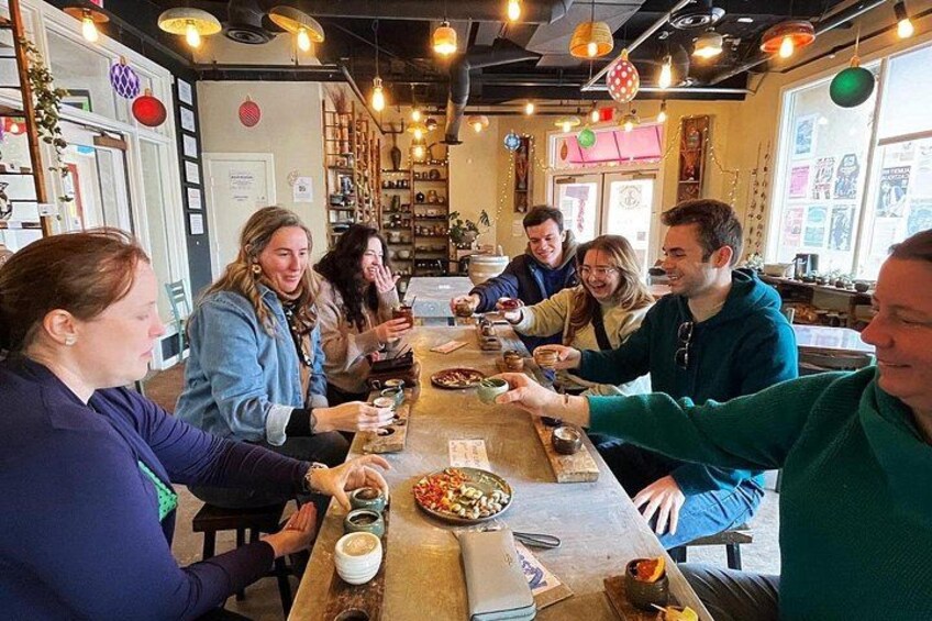 A group of people seated around a long table in a restaurant with various dishes and drinks. 2