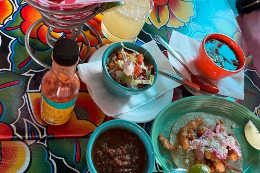A colorful table with various dishes, including a bowl of beans, a plate of enchiladas, and a red cup. 3