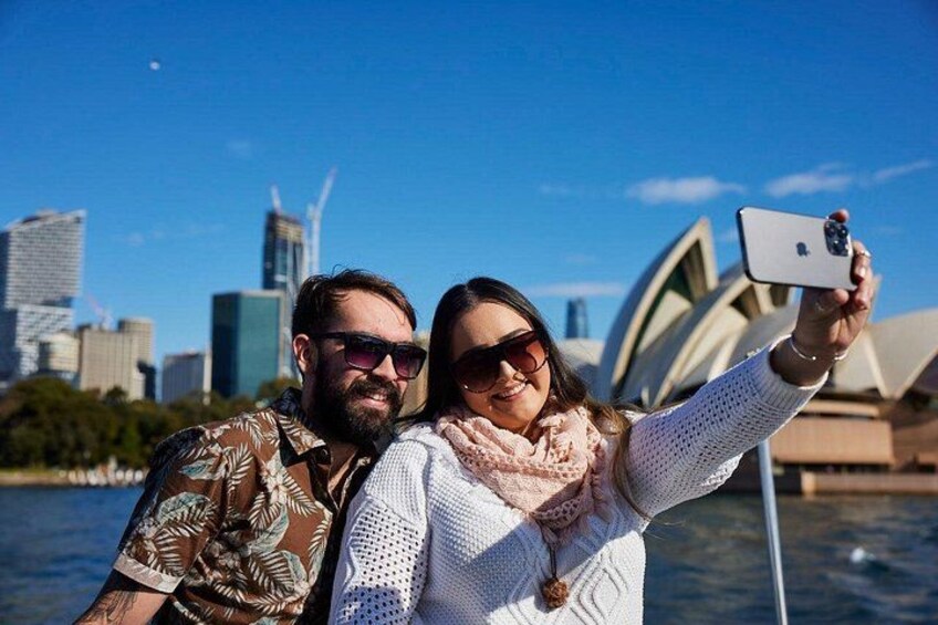 Two people taking a selfie with the Sydney Opera House in the background. 2