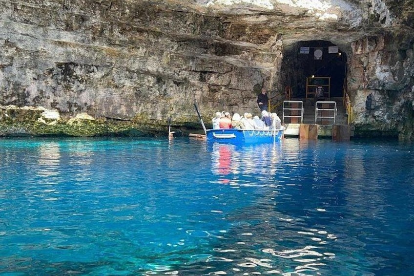 A boat with people in a clear blue pool with rocky walls. 4