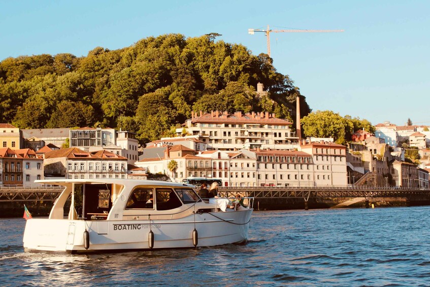 Valkoinen vene, jonka kylkeen on maalattu teksti »BOATINGPORT.COM», on ankkuroitu lähelle rantaviivaa, taustalla näkyy rakennuksia ja kukkula. 1