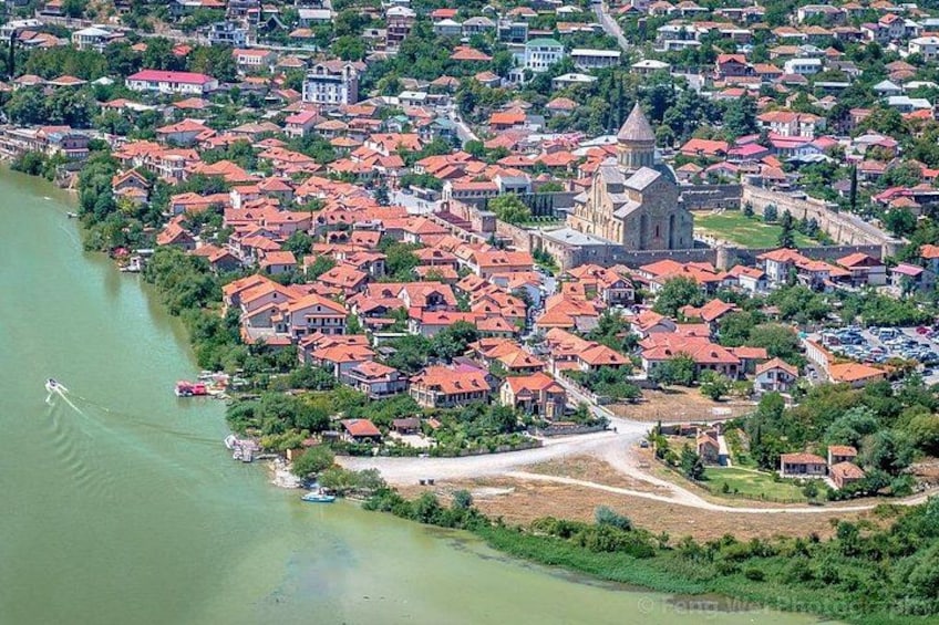 A river with boats, a town with red-roofed houses, and a prominent church. 4