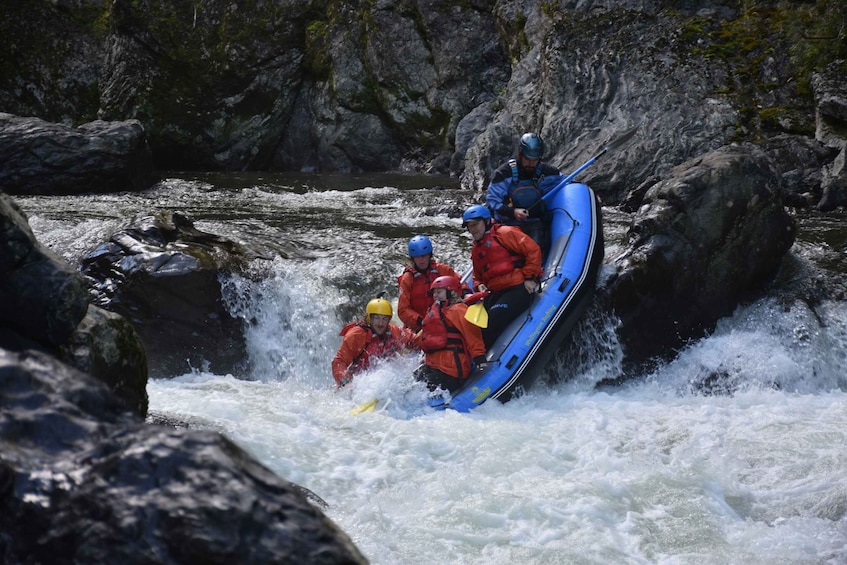 Un grupo de personas en una balsa azul navegando un río con rápidos. 4