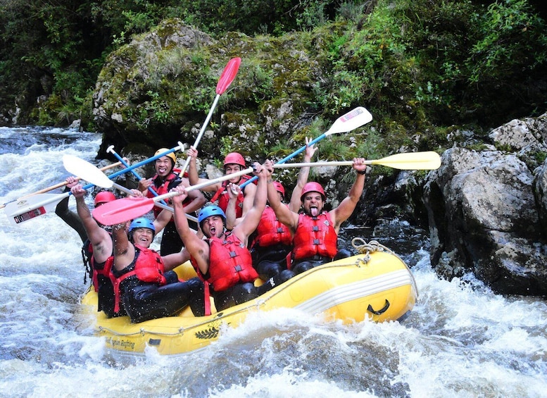 Un grupo de personas en un bote inflable amarillo navegando un río con rápidos. 1