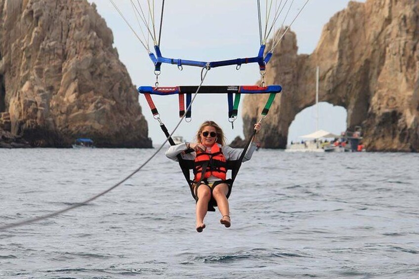 Iemand die parasailt boven het water, met een rotsachtige kustlijn op de achtergrond. 2