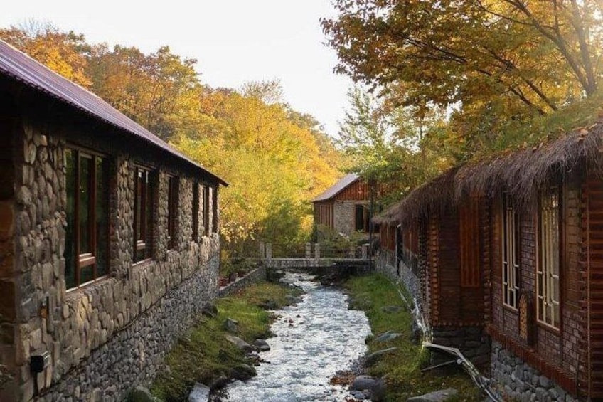 Ein Steinhaus mit einem hölzernen Anbau neben einem Bach. 2