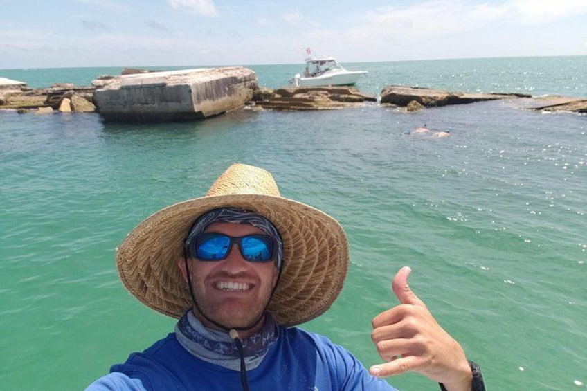 Una persona con un cappello di paglia e una camicia blu che fa il gesto dell'ok con il pollice. 5