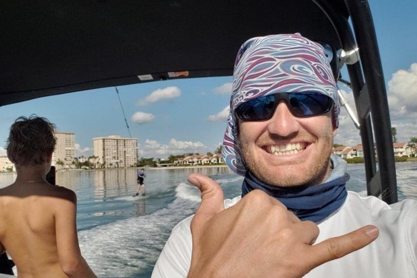 Una persona su una barca, con un appassionato di wakeboard sullo sfondo. 4