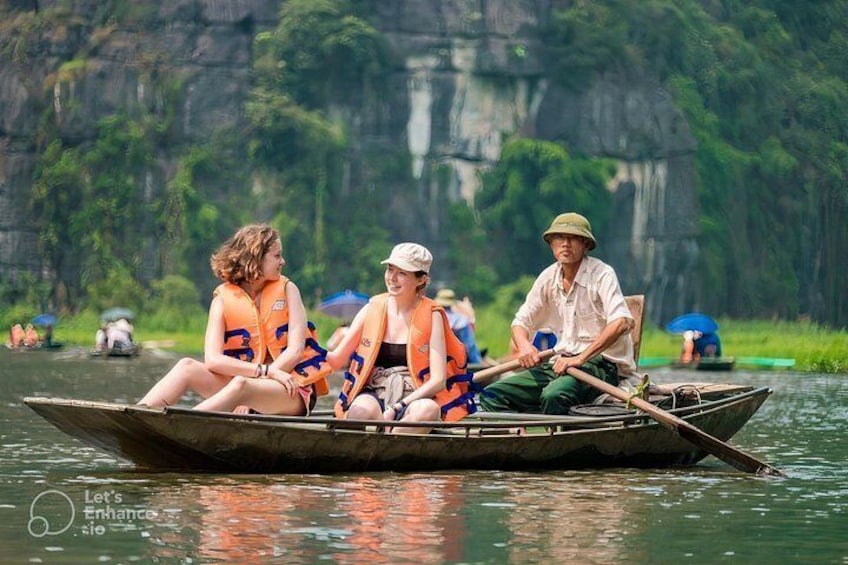 A group of people in a boat on a river with a forested cliff in the background. 2