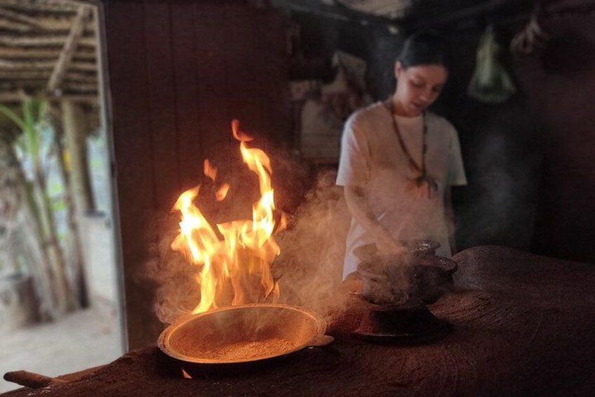 A fire burning in a pan, with smoke rising, and a person standing in the background. 2
