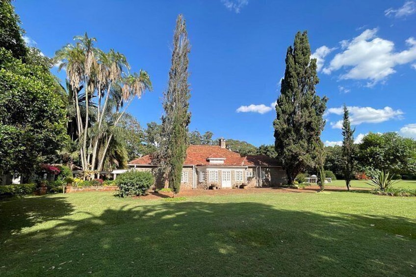 Una casa con techo rojo, rodeada de un césped cuidado y árboles altos. 4