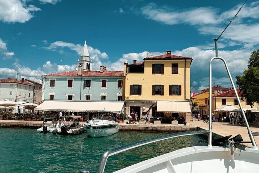 A waterfront with boats docked, a yellow building, and a church tower. 5