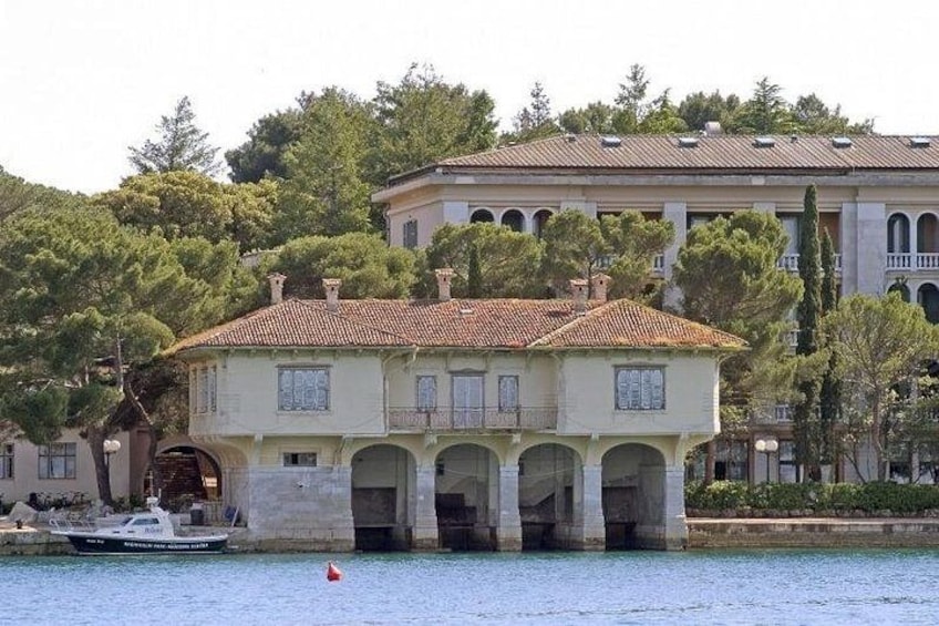 Une maison située sur la côte, avec un toit en tuiles, de nombreuses arcades et un bateau amarré à proximité. 5