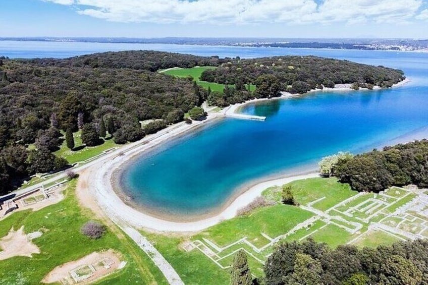 A coastal landscape with a large body of water, a sandy beach, and a forested area. 1
