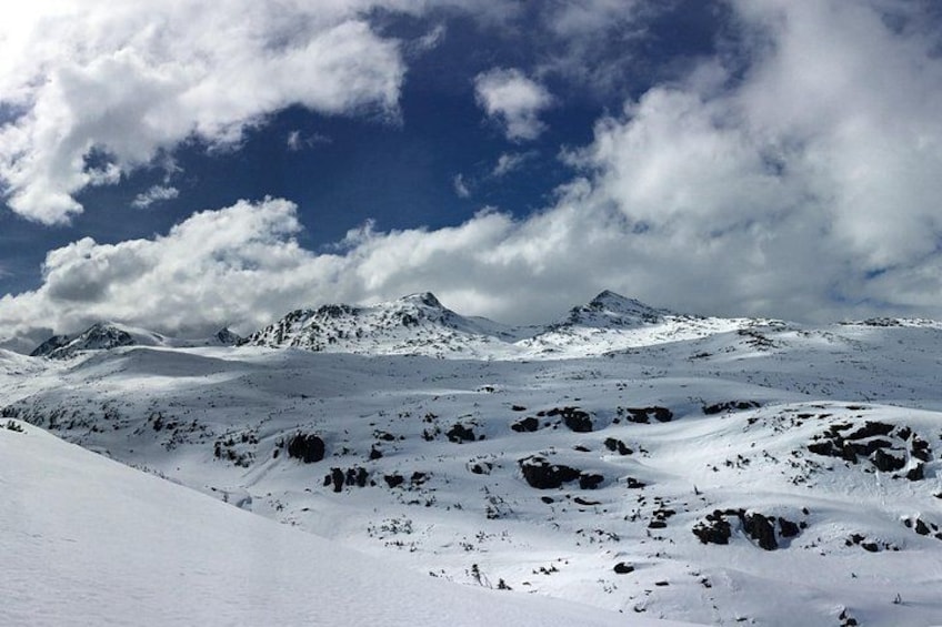 A snow-covered mountain range under a partly cloudy sky. 2