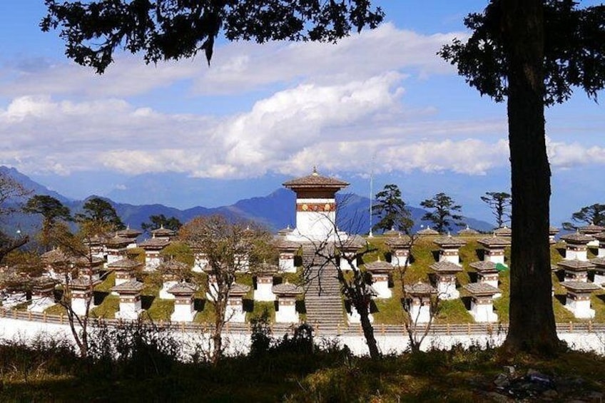A traditional Tibetan monastery with a central stupa, surrounded by smaller buildings and a mountainous backdrop. 2