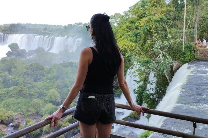 A person standing by a railing overlooking a waterfall. 5