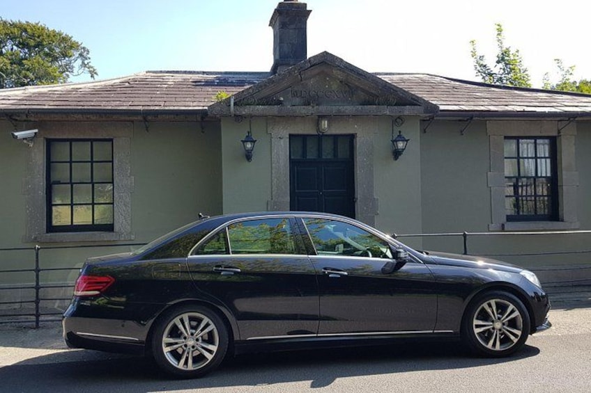 A black sedan parked in front of a building with a gabled roof and a chimney. 4
