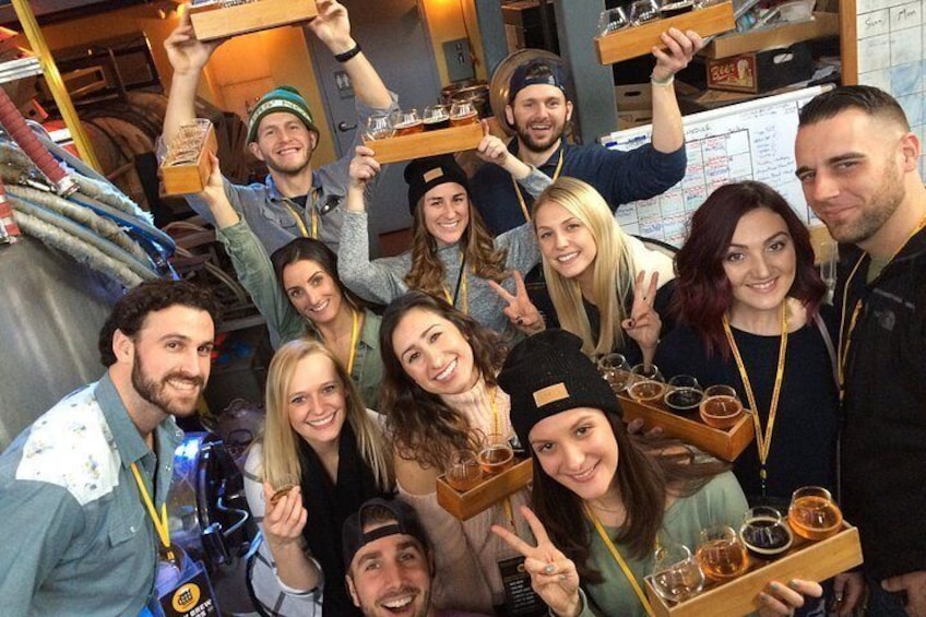A group of people holding glasses and boxes, likely in a bar or tasting room. 4