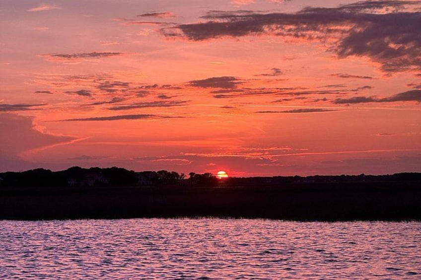 A sunset over a body of water with a silhouette of a distant shoreline. 5