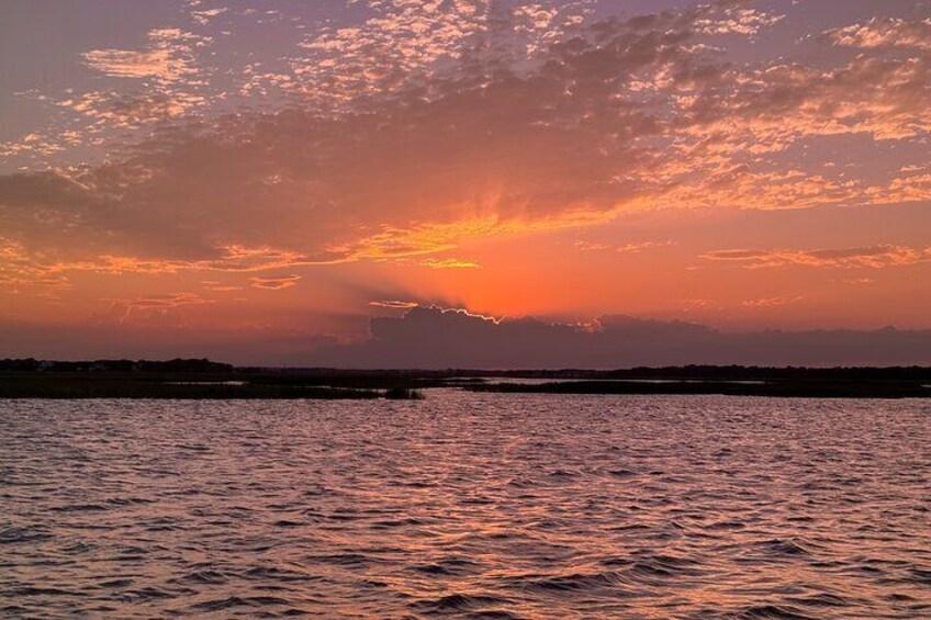A sunset over a body of water with a distant shoreline. 2