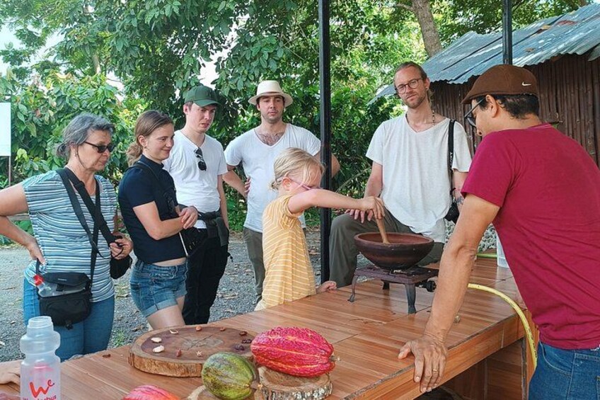 Un grupo de personas alrededor de una mesa de madera con comida y una olla. 4