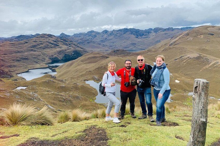Un grupo de personas de pie en una colina cubierta de hierba, con un lago y montañas al fondo. 3