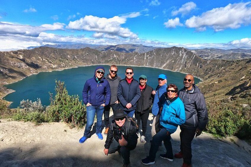 A group of people standing on a mountain overlooking a lake. 3