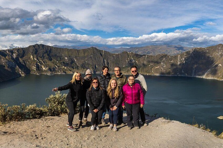 Un grupo de personas en un saliente rocoso, con vistas a un lago y montañas al fondo. 2