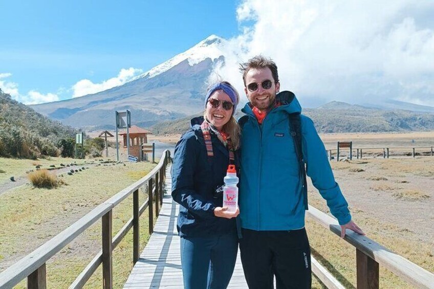 Two people on a wooden boardwalk with a mountain in the background. 1