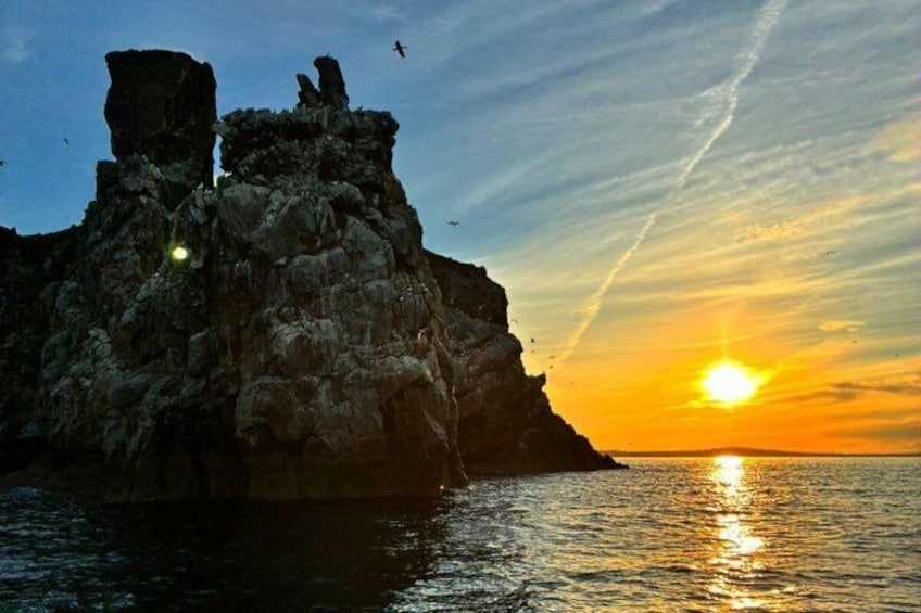 A rocky coastline at sunset with the sun low on the horizon. 4