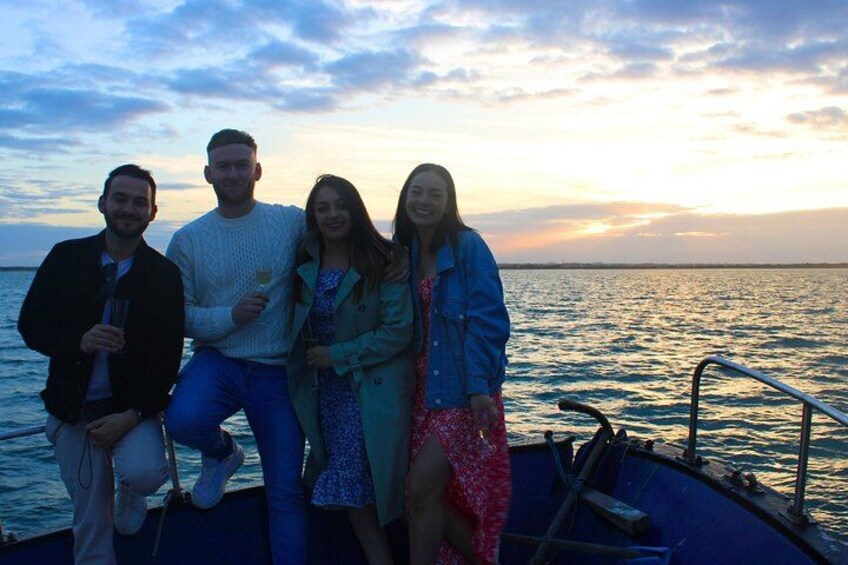 A group of people on a boat with a sunset in the background. 4
