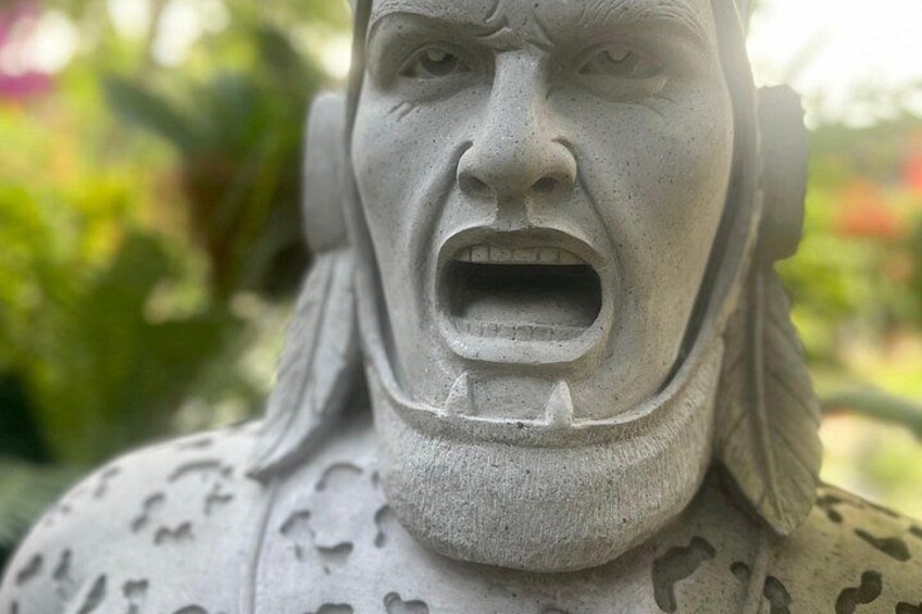 Een stenen standbeeld met een grimmige uitdrukking, gedetailleerde gezichtskenmerken en een bladpatroon op het lichaam. 3