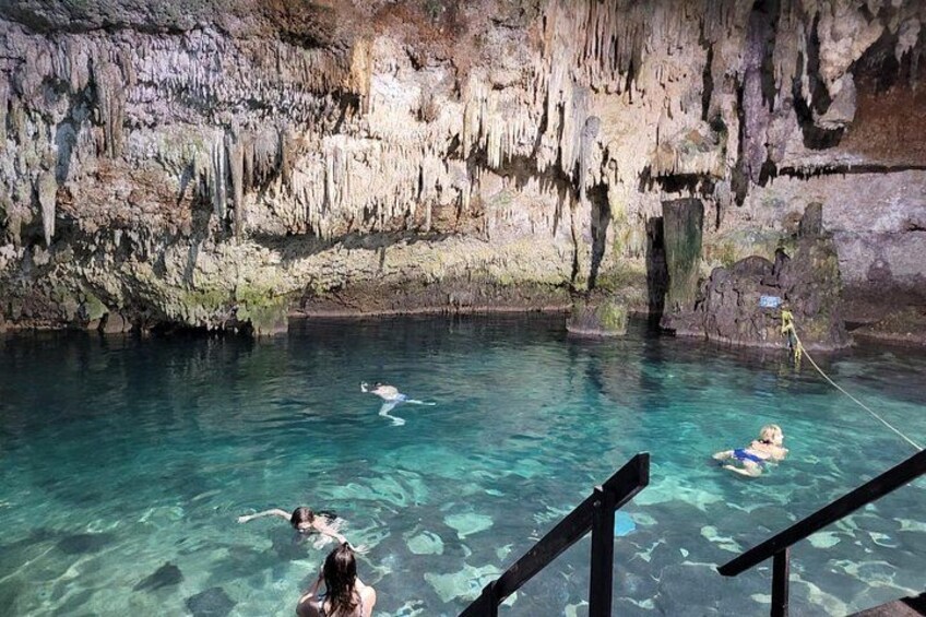A clear pool with people swimming and a rocky cave wall in the background. 5