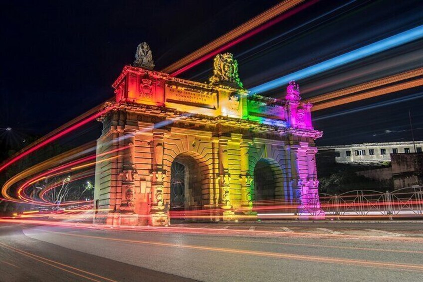A brightly lit arch with colorful lights, surrounded by a road with light trails from moving vehicles. 1