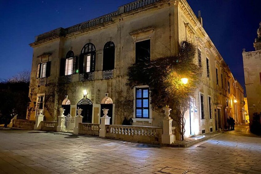 A historic building with arched windows and a courtyard at night. 2