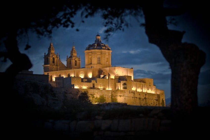 A historic building with multiple domes and towers, illuminated at dusk. 5